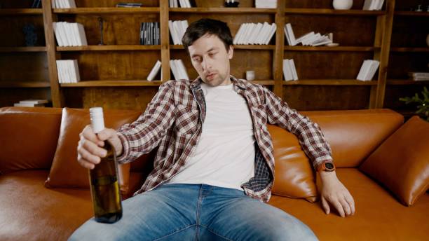 istock Alcohol addiction at young age. Caucasian male cannot stop drinking alcohol, drunken lonely male drinks wine from bottle. Loneliness, depression and alcoholism during Christmas and New Year holidays 1292316041