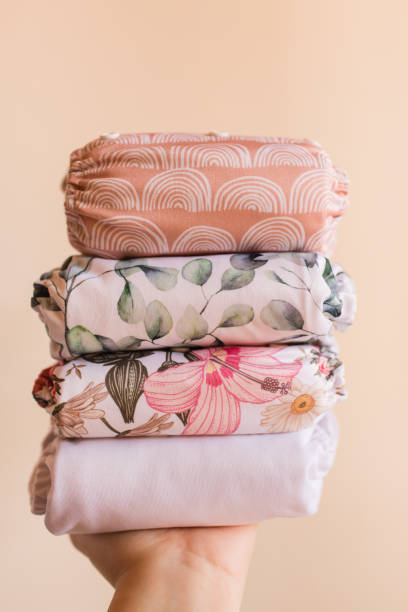 istock A Woman Holding a Stack of Modern Neutral-Colored Reusable Cloth Diapers with a Neutral Background in Bright Natural Light 1292319531