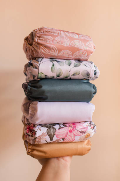 istock A Woman Holding a Stack of Modern Neutral-Colored Reusable Cloth Diapers with a Neutral Background in Bright Natural Light 1292319770