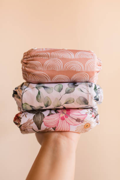istock A Woman Holding a Stack of Modern Neutral-Colored Reusable Cloth Diapers with a Neutral Background in Bright Natural Light 1292319797