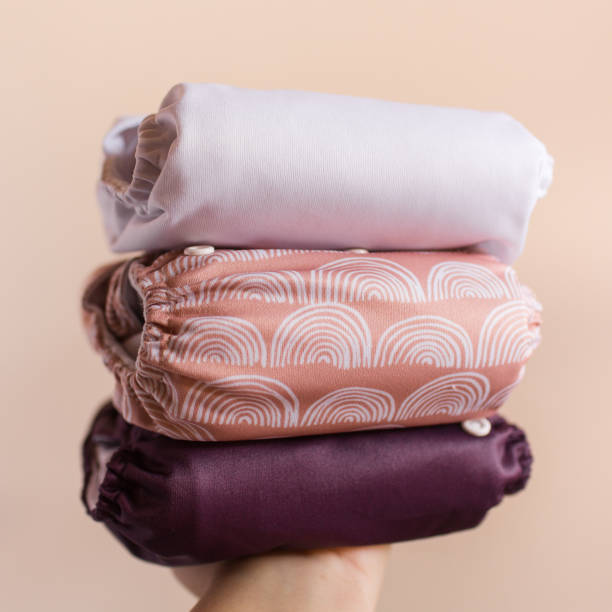 istock A Woman Holding a Stack of Modern Neutral-Colored Reusable Cloth Diapers with a Neutral Background in Bright Natural Light 1292320328