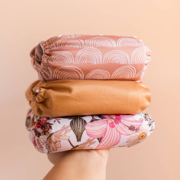 istock A Woman Holding a Stack of Modern Neutral-Colored Reusable Cloth Diapers with a Neutral Background in Bright Natural Light 1292320542