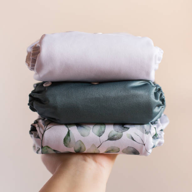 istock A Woman Holding a Stack of Modern Neutral-Colored Reusable Cloth Diapers with a Neutral Background in Bright Natural Light 1292320989
