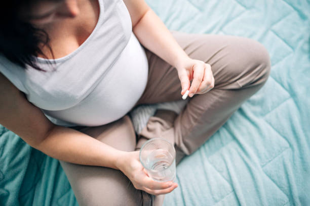 mujer embarazada tomando píldora en casa - ion fotografías e imágenes de stock