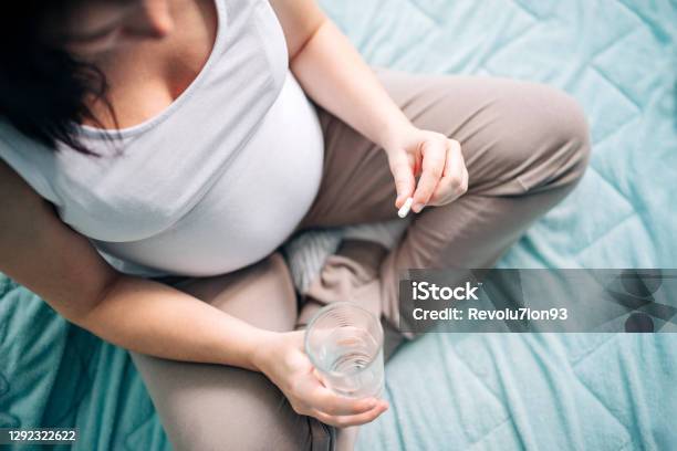 Pregnant Woman Taking Pill At Home Stock Photo - Download Image Now - Pregnant, Folic Acid, Capsule - Medicine