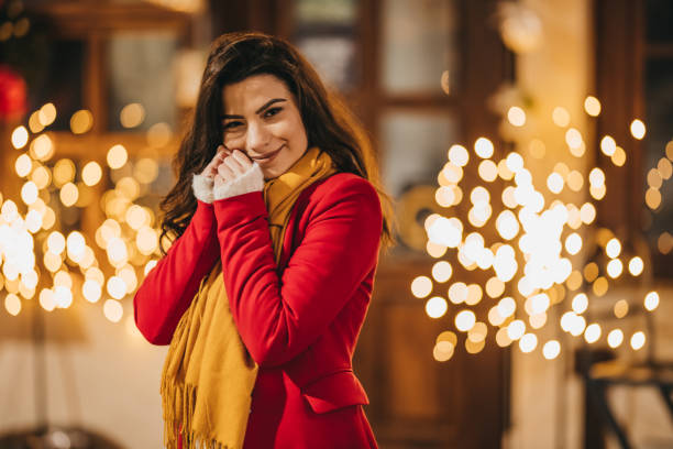 Beautiful young woman enjoying festive mood among Christmas lights in the city at night
