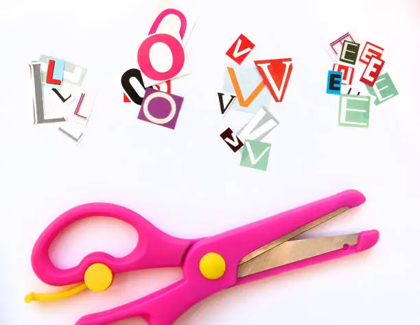 many cut letters to compose word LOVE and scissors. Paper cut letters. Newspaper magazine uppercase cutouts