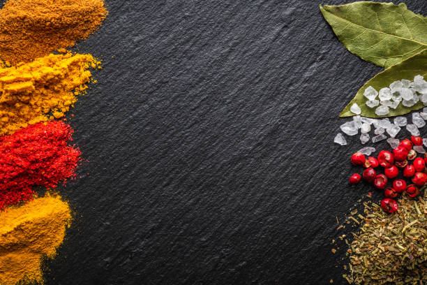 istock Bright and colorful spices on the black stone background. Different spices and herbs for background. 1292331855