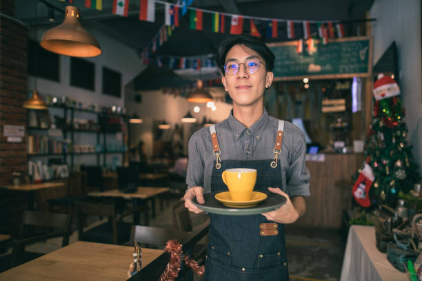 istock Asian cafe worker bring coffee for customer in cafe 1292331997