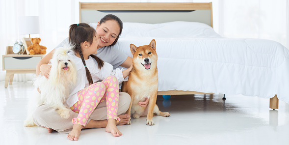 Asian mom and daughter with a dog in the bedroom.