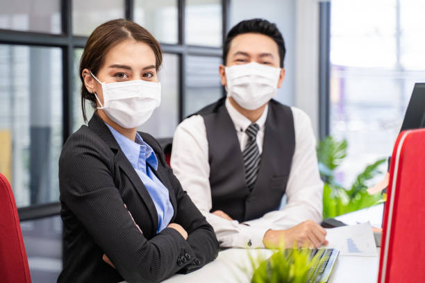 Group of Asian team business people working in office with new normal social distancing lifestyle concept. Man and woman wear protective face mask and keep distancing to prevent COVID virus in company grupo de empresarios del equipo asiático que trabajan en la oficina con un nuevo concepto normal de estilo de vida de distanciamiento social. hombre y mujer usan mascarilla protectora para la cara y siguen distanciando para prevenir el virus covid en comp