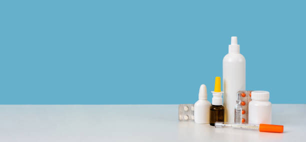 istock Banner with copy space. Medicine supplies setup: mercury thermometer, white plastic bottle, ampule, pills and nasal spray. Bright blue background. Home medicine chest or pharmacy concept. Closeup 1292346091