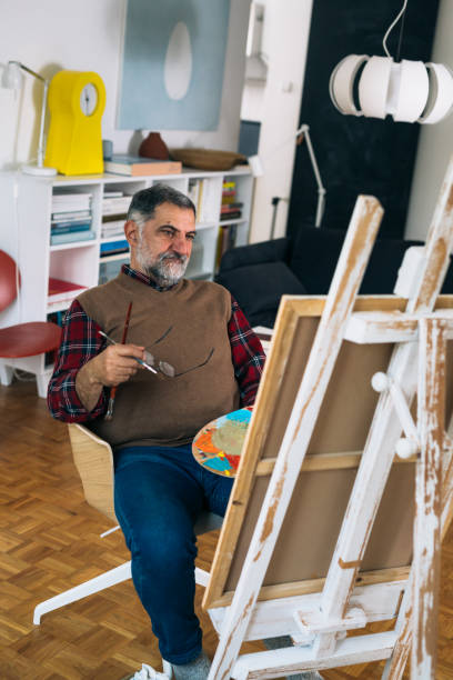istock senior man relaxing at home and painting 1292357780