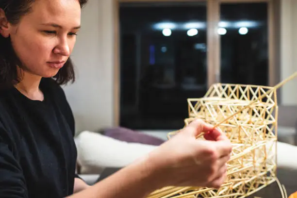A young woman making a traditional Finnish decoration - Himmeli, made from natural straws. Perfect hobby and meditation.