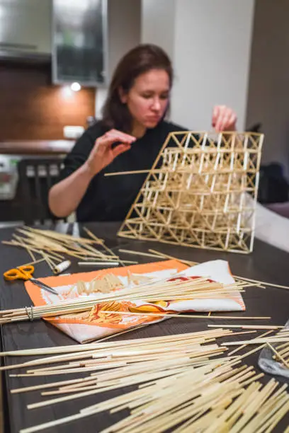 A young woman making a traditional Finnish decoration - Himmeli, made from natural straws. Perfect hobby and meditation.