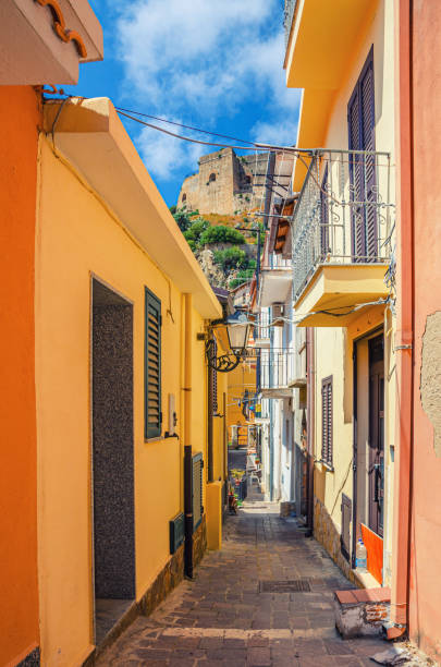 Narrow pedestrian street between buildings with colorful walls in seaside small town Scilla, old medieval castle Castello Ruffo Narrow pedestrian street between buildings with colorful walls in seaside small town Scilla, old medieval castle Castello Ruffo background, Calabria, Southern Italy castle scilla stock pictures, royalty-free photos & images