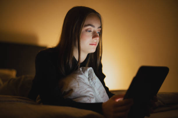istock Young woman lying on bed relaxing with digital tablet 1292360393