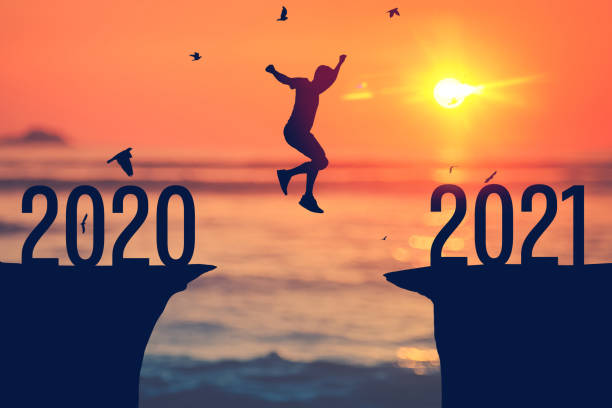 istock Silhouette man jumping between cliff with number 2020 to 2021 at tropical sunset beach. Freedom challenge and travel adventure holiday concept. 1292361962