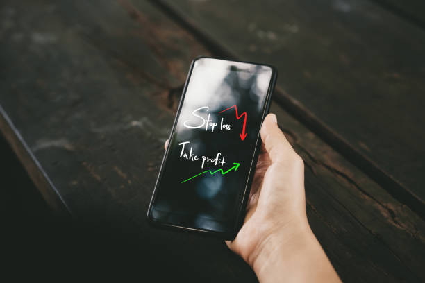 Woman hand using smart phone with stop loss take profit and graph chart pattern on screen at coffee shop. Technology business and freedom trader concept.