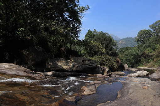 Water flows downstream through the rocky riverbed of the 'Marmala' waterfalls in the western ghats of Kerala, India.