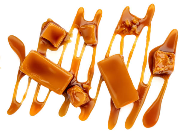 istock Sweet Caramel candies and syrup topping isolated on a white background. Creative layout made of caramel  closeup. Flat lay. Food concept.