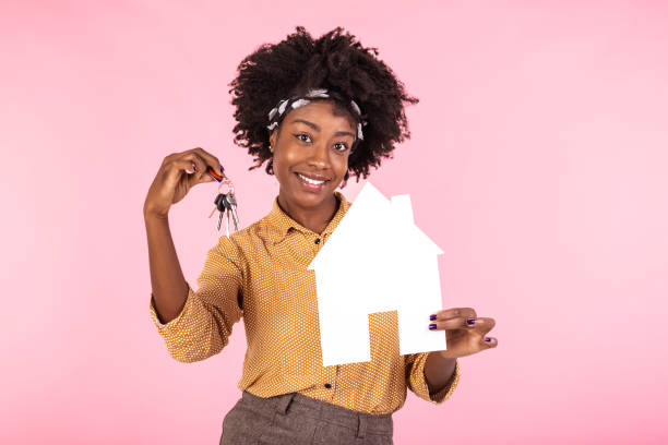 Happy young african american woman in casual shirt hold house and bunch of apartment keys, isolated on pink background studio portrait. People lifestyle concept. Mock up copy space. Happy young african american woman in casual shirt hold house and bunch of apartment keys, isolated on pink background studio portrait. People lifestyle concept. Mock up copy space. home ownership women stock pictures, royalty-free photos & images