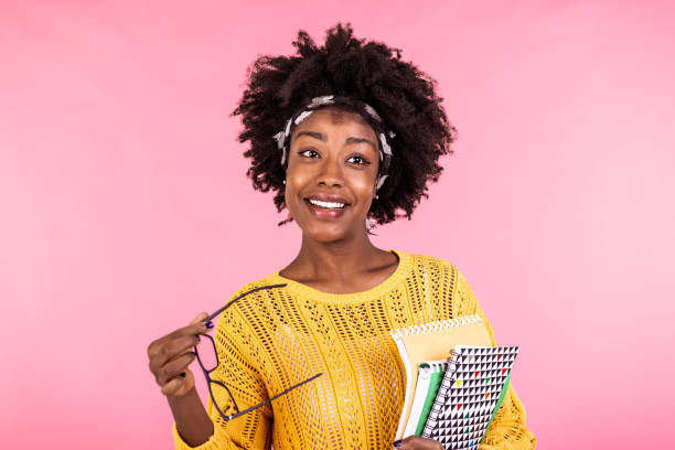 Smiling African American girl student or woman teacher portrait with books in hands. education, high school and people concept - happy smiling young woman teacher in glasses Smiling African American girl student or woman teacher portrait with books in hands. education, high school and people concept - happy smiling young woman teacher in glasses black nerd stock pictures, royalty-free photos & images