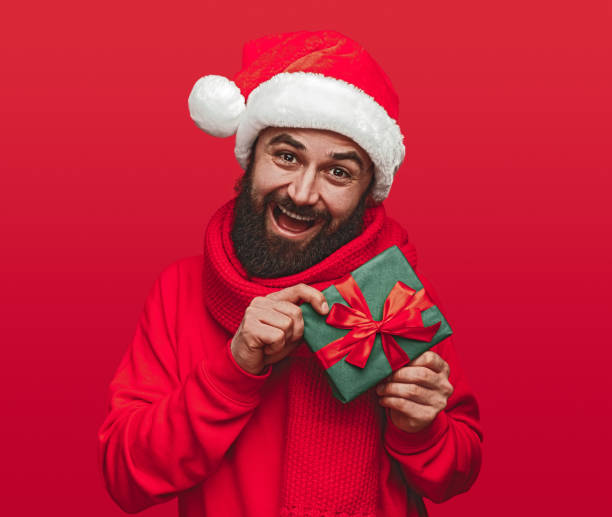 istock Excited man in Santa hat on red background 1292366916