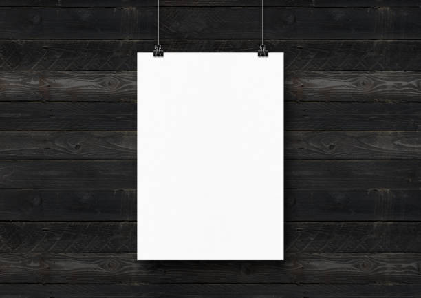 istock White poster hanging on a black wooden wall with clips 1292367677