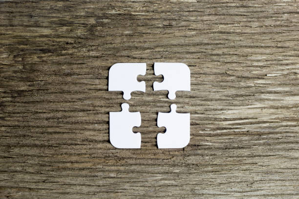 4 pieces of a puzzle do not fit together causing a difficult problem to solve. problems in work and team cooperation. the white pieces are located in the middle of the image on an old wooden background with space for copying around - document file emotional stress paperwork imagens e fotografias de stock