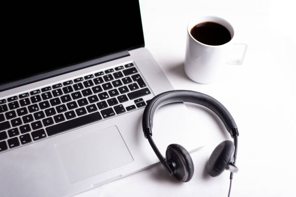 Headset and a laptop on a wooden table, view from above. Call center, home office, customer support, help desk concept