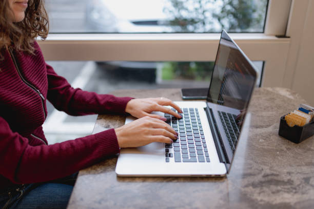 istock Close-up unrecognizable woman hands typing on computer keyboard in a cafe. 1292370650