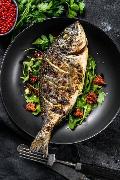 istock Grilled Dorado fish with arugula salad and tomatoes. Black background. top view 1292370945