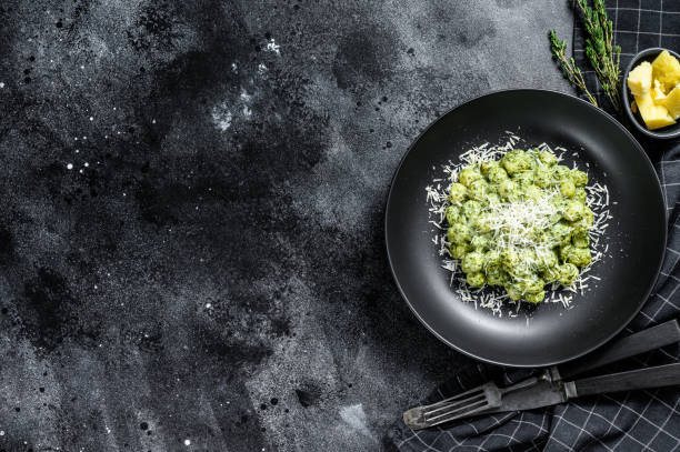 istock Gnocchi with basil spinach sauce and Parmesan. Italian potato paste. Black background. Top view. Copy space 1292373226