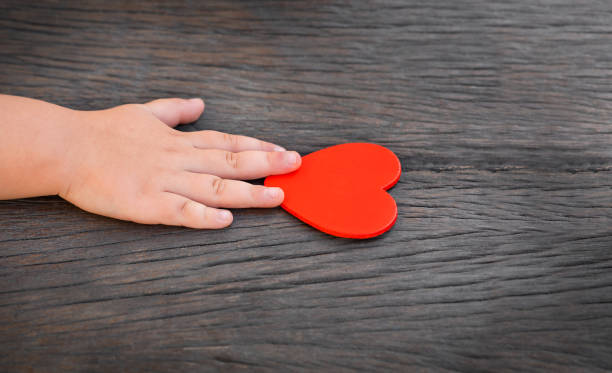 istock child hand reaches for red heart 1292374265
