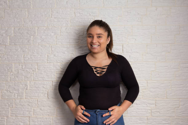 woman smilling at camera Portrait of Confident overweight woman smilling at camera. Isolated on white brick wall plus size woman fashion laughing stock pictures, royalty-free photos & images
