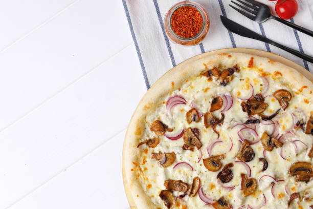 istock Pizza with mushrooms and onion on board on white wooden table 1292376763