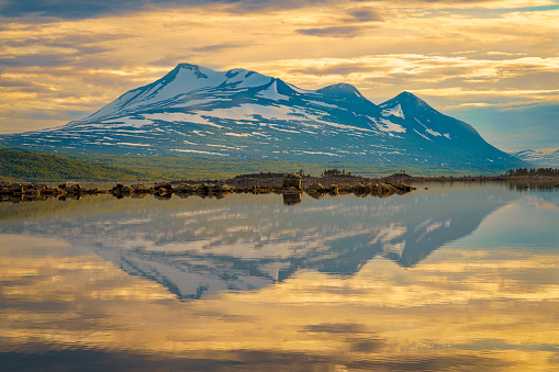 View over Mount Akka reflecting in the water, in nice evening light in the summer nigh, Stora sjöfallet nationalpark, Swedish Lapland, Sweden