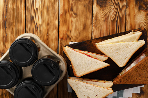 Four cups of coffee and four sandwiches on wooden table top view