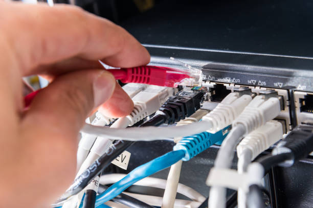 istock Hand of computer engineer connecting fiber optic cable 1292382511