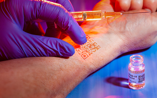 Concepto de teoría de la conspiración con chip de identificación implantado en el brazo del paciente durante la vacunación COVID-19 photo