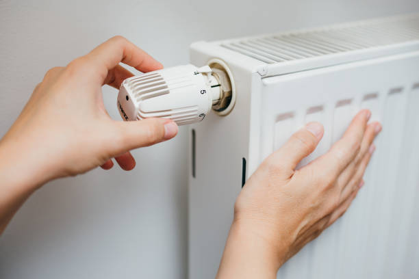 istock Female hand adjusting radiator temperature on thermostat 1292383913