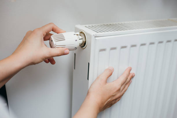 istock Female hand adjusting radiator temperature on thermostat 1292384592