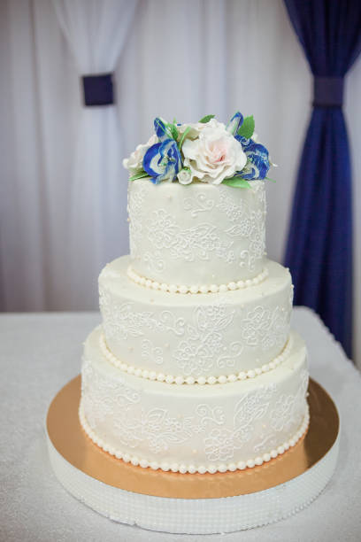 Three-tier white wedding cake decorated with white and blue flowers