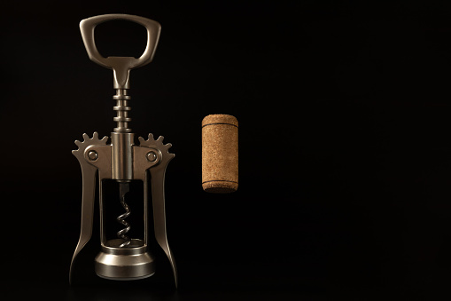 Top view of a vintage corkscrew and wine cork stopper shot on white background. The composition is at the right of an horizontal frame leaving a useful copy space for text and/or logo. High key DSRL studio photo taken with Canon EOS 5D Mk II and Canon EF 100mm f/2.8L Macro IS USM.