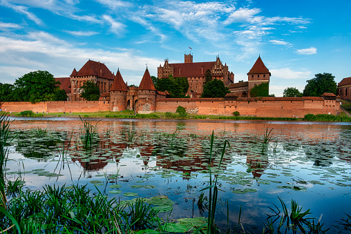 Malbork, Poland - 27.07.2020:Brick gothic Malbork castle on the river Nogat, Poland. Under the walls of the castle is a medieval encampment lovers of the Middle Ages