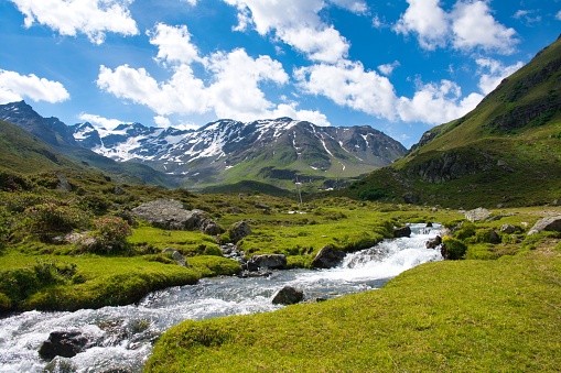 mountain panorama with raging river through the green fields. Autumn winter landscape from Davos Dischma Durrboden Switzerland. Mountain peak with snow