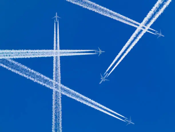 Several planes with white contrails from white skies