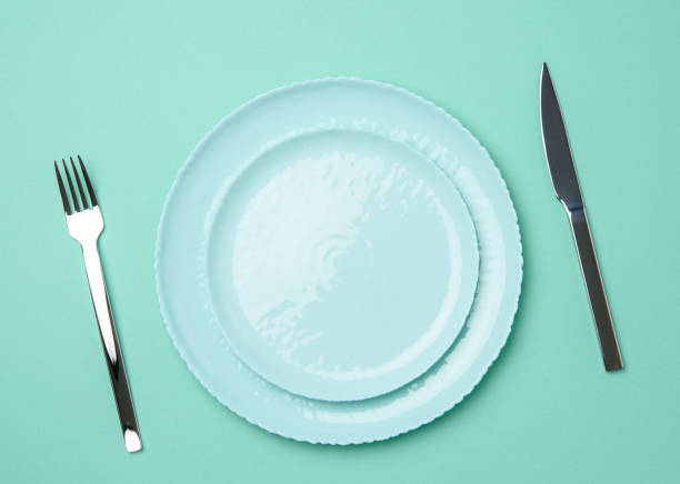 istock round ceramic plates, fork with knife on a green background 1292392997