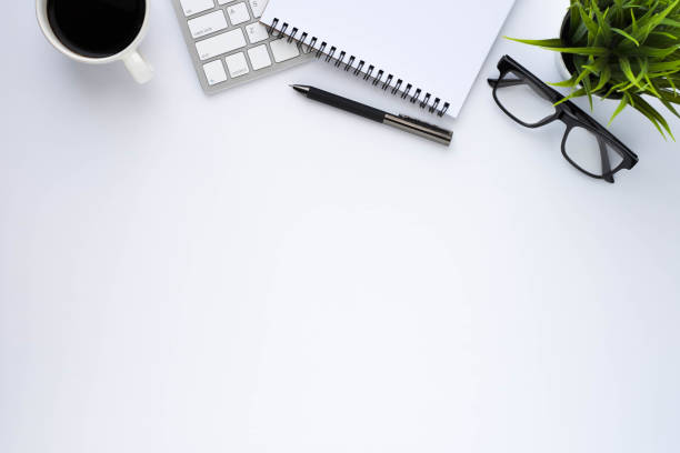 istock Top view above of White office desk table with keyboard, notebook and coffee cup with equipment other office supplies. Business and finance concept. Workplace, Flat lay with blank copy space. 1292395469